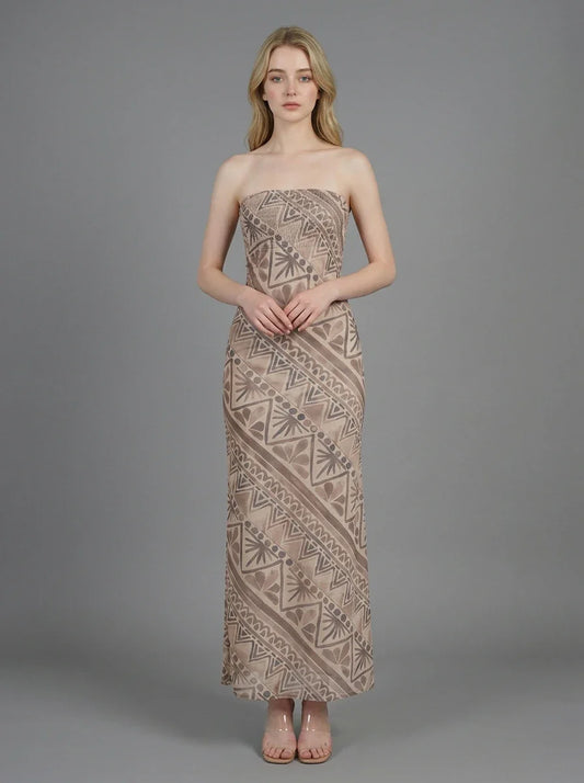 Woman wearing a strapless, patterned maxi dress standing against a grey background, front view.