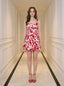 Woman standing in a hallway wearing a red and white floral print dress and red strappy heels