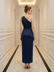 Back view of a woman in a navy blue satin one-shoulder gown with a high slit