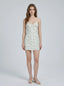 Woman wearing a white floral print mini dress with spaghetti straps and a sweetheart neckline, standing against a white background.