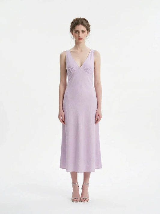 Model wearing a lavender midi dress with a V-neckline and sleeveless design, standing against a white background.