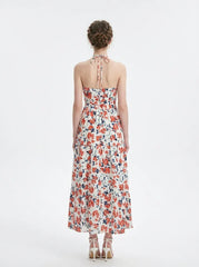 Back view of a woman wearing a white floral print maxi dress with a halter neckline and tiered skirt, standing against a white background.