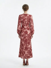 back view of a woman wearing a pink and red floral print satin maxi wrap dress with long bishop sleeves and a v-neck, standing against a white background
