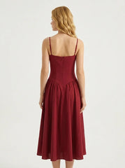 Woman wearing a deep red fit and flare midi dress with spaghetti straps, back view