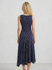 Rear view of a woman wearing a navy blue sleeveless midi dress with white polka dots.