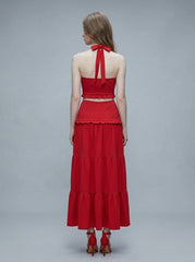 Woman wearing a red halter crop top and a tiered maxi skirt, back view