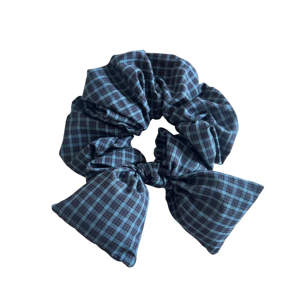 Oversized scrunchie with a dark blue and black plaid pattern and a matching bow detail.