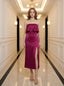 Woman wearing a strapless magenta satin midi dress with a high slit, standing in a hallway.