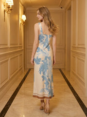 Back view of a woman wearing a cream and blue floral print satin midi dress, standing in a hallway.