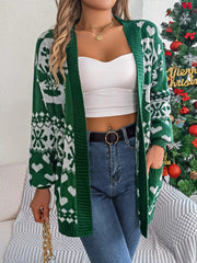 Woman wearing a green and white Fair Isle knit cardigan with an open front and pockets, standing in front of a Christmas tree.