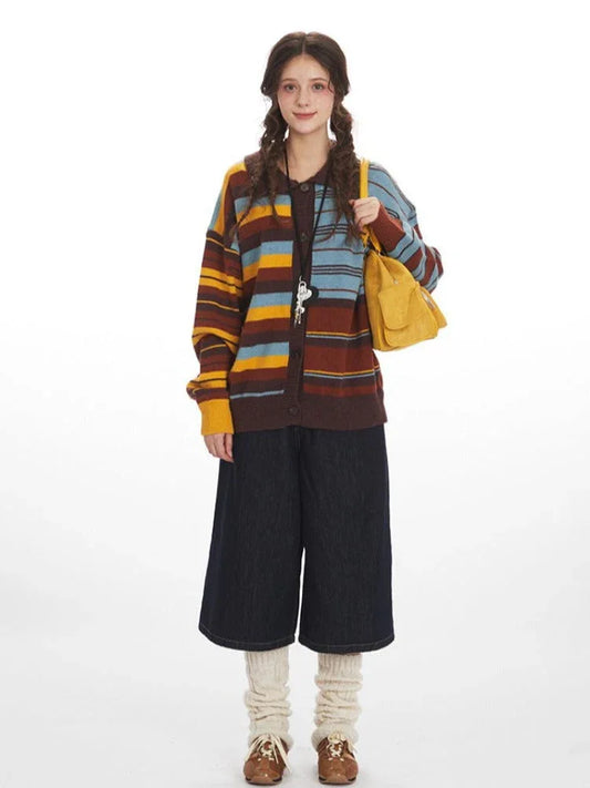 Woman wearing a striped knit cardigan with wide-leg dark denim pants and cream leg warmers, holding a yellow handbag.