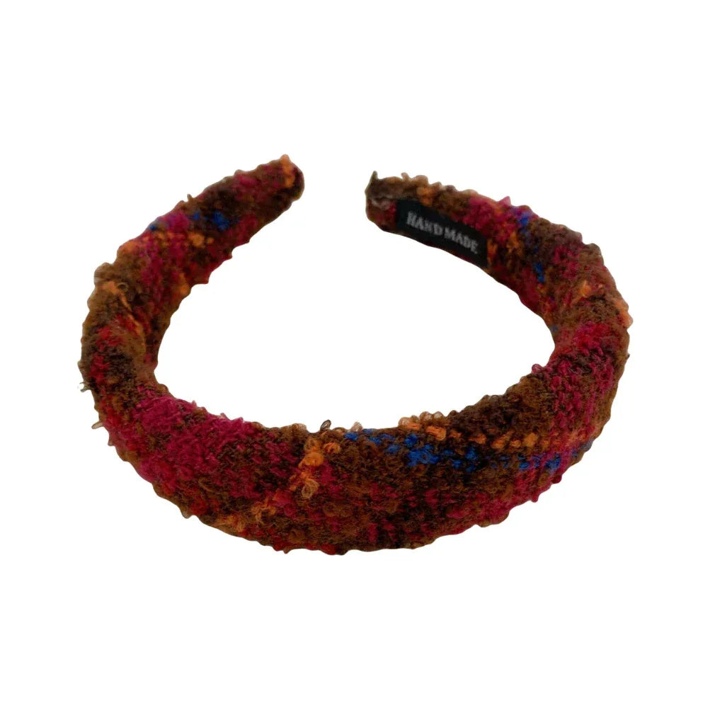 A single headband with a textured plaid fabric in red, brown, and blue tones.
