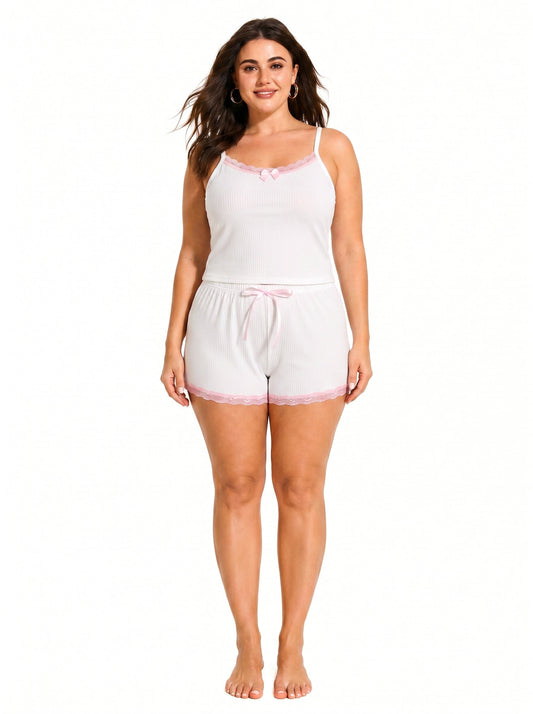 Woman wearing a white ribbed camisole and shorts pajama set with pink lace trim and bow accents.