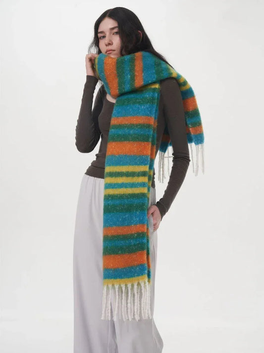 Woman wearing a long-sleeved dark top and light grey pants, with a colorful striped scarf draped around her neck.