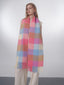 Close-up of the plaid pattern on the fuzzy knit scarf, showing the pink, blue, and tan colors and fringe.