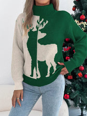 Woman posing in a green and cream knit sweater with a reindeer graphic and a turtleneck.