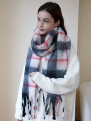 Woman wearing a cream-colored sweater and a plaid scarf, looking to the side.