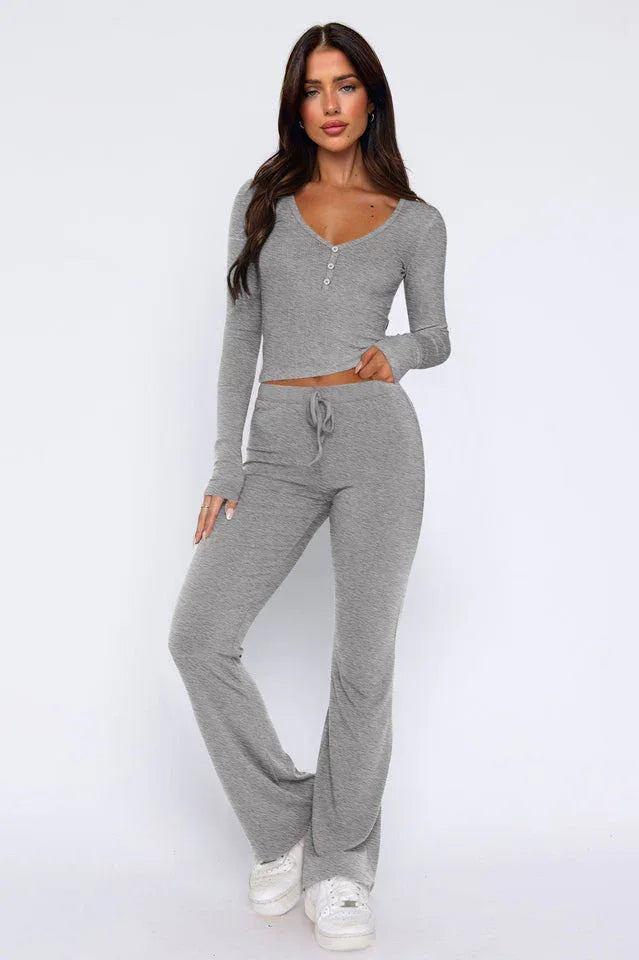 Woman wearing a grey ribbed knit long-sleeve top with button detail and matching flared pants, front view.