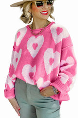 Woman wearing a pink knit sweater with a heart pattern and pearl embellishments.