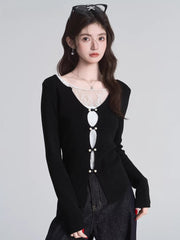 Close-up of a woman wearing a black long-sleeved top with white lace trim and decorative buttons.