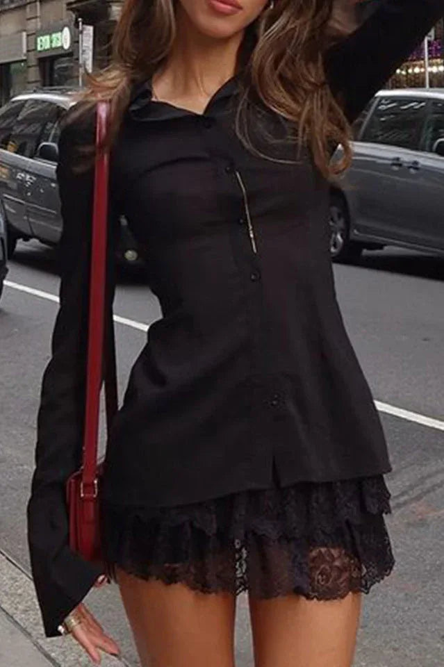 Woman wearing a black collared shirt with a lace trim hem and a red crossbody bag, standing on a city street.