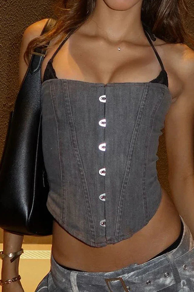 Close-up of a woman wearing a grey denim-like halter corset top with a black lace bralette underneath and a black handbag over her shoulder.