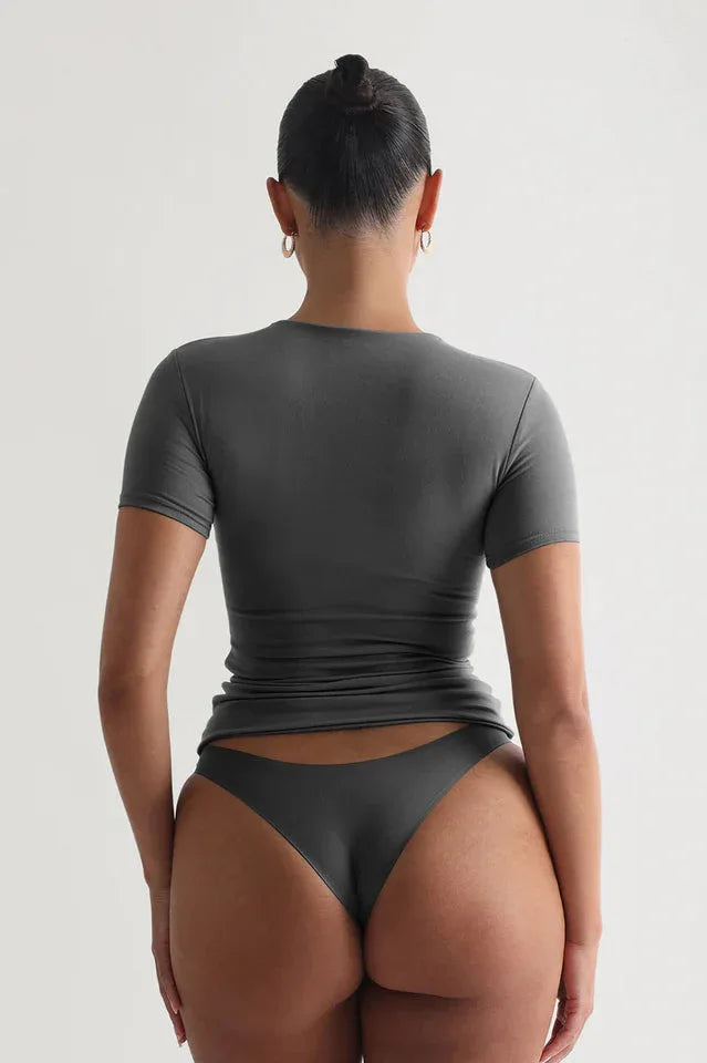 Back view of a woman wearing a grey short-sleeve t-shirt and grey underwear