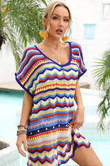 Woman wearing a colorful striped crochet knit tunic with a v-neck and short sleeves, accessorized with yellow earrings.