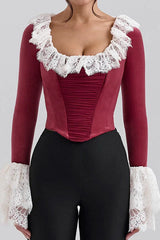 Woman wearing a red velvet top with white lace trim and ruffled collar and cuffs, front view