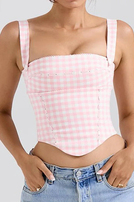 Woman wearing a pink and white gingham corset top with denim jeans.