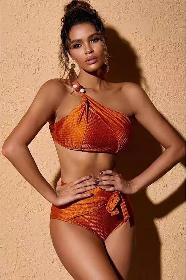 Close-up of a woman wearing an orange one-shoulder bikini top and high-waisted bottoms