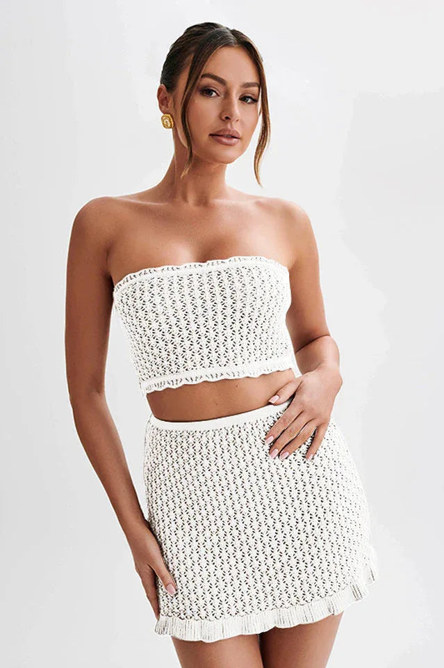 Woman wearing a white crocheted tube top and mini skirt, front view