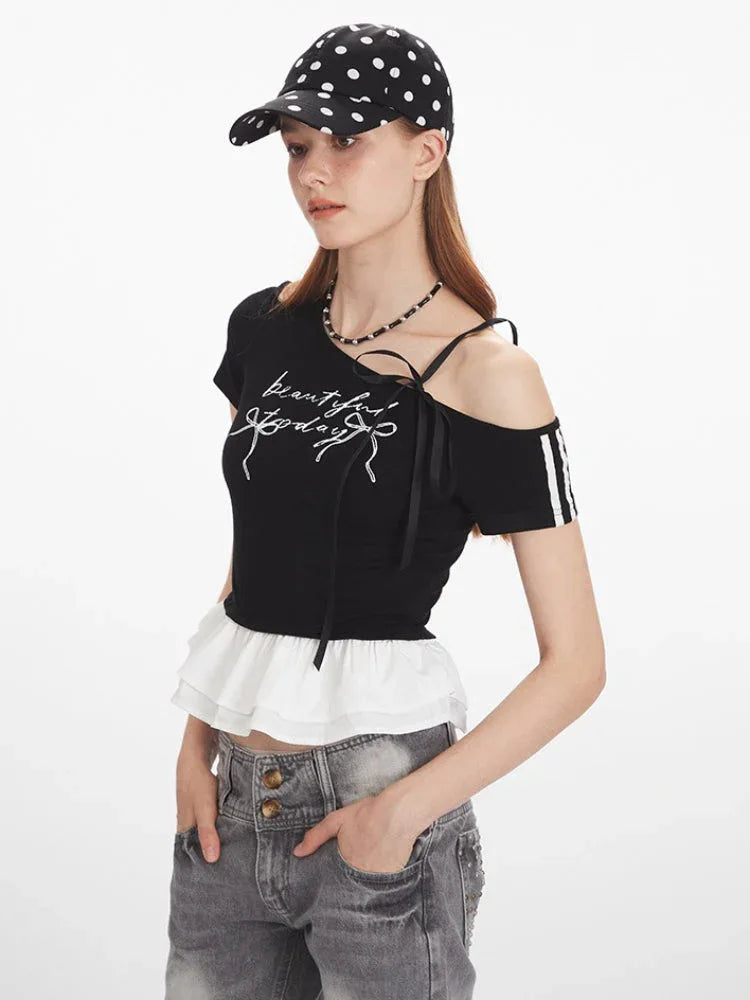 Close-up of a woman wearing a black off-the-shoulder top with graphic print and white ruffle trim.