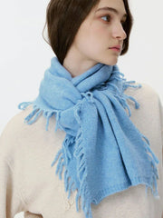 Close-up of a woman wearing a light blue scarf with fringe.