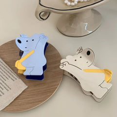 White and blue bear-shaped hair clips on a wooden coaster