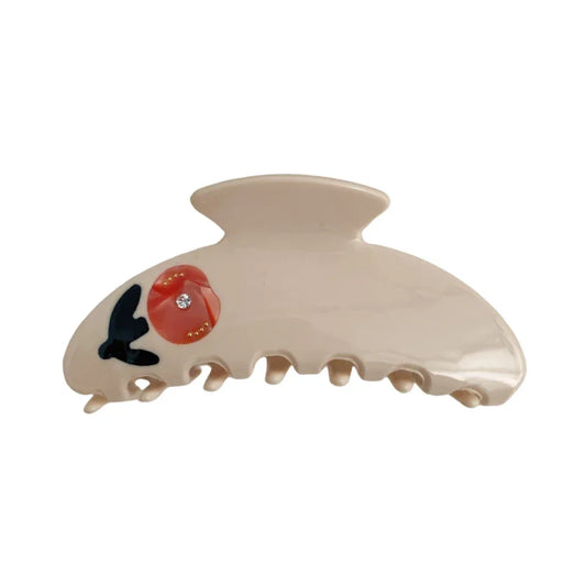 A cream-colored claw clip with a red floral design and a small gemstone.