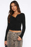 Woman wearing a black long-sleeve cropped top with button-up front and leopard print pants