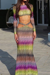 Woman standing outdoors wearing a long sleeve crop top and maxi skirt with abstract print and cut-out details