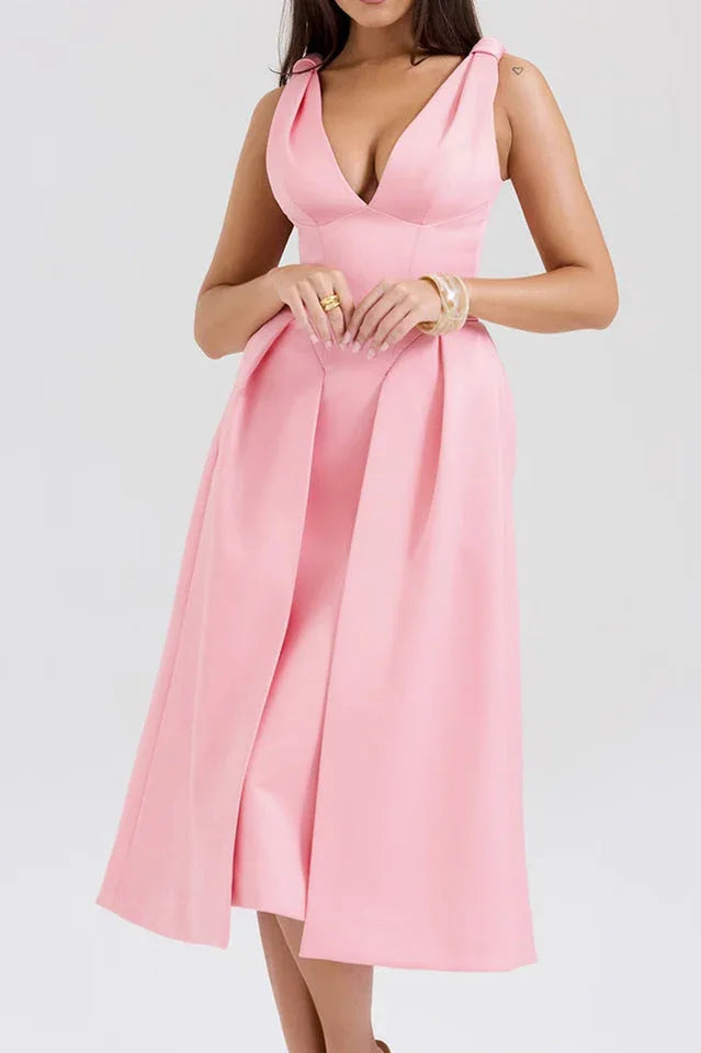 Woman wearing a pink midi dress with a deep V-neck and pleated skirt.