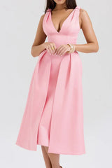 Woman wearing a pink midi dress with a deep V-neck and pleated skirt.
