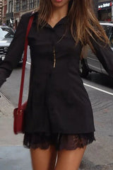 Woman wearing a black collared shirt with a lace trim hem and a red crossbody bag, walking on a city street.