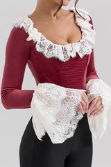 Woman wearing a red velvet top with white lace trim and ruffled collar and cuffs, close-up front view