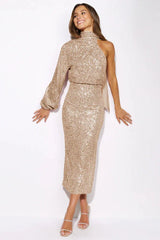 Woman in a gold sequin one-shoulder midi dress with a high neckline and a side slit, shown from the front.