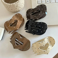 Five heart-shaped hair claw clips displayed on a white surface, featuring a polka dot design in black, cream, and brown.