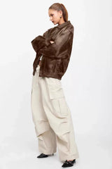 Side view of a model in a brown faux leather jacket and beige cargo pants