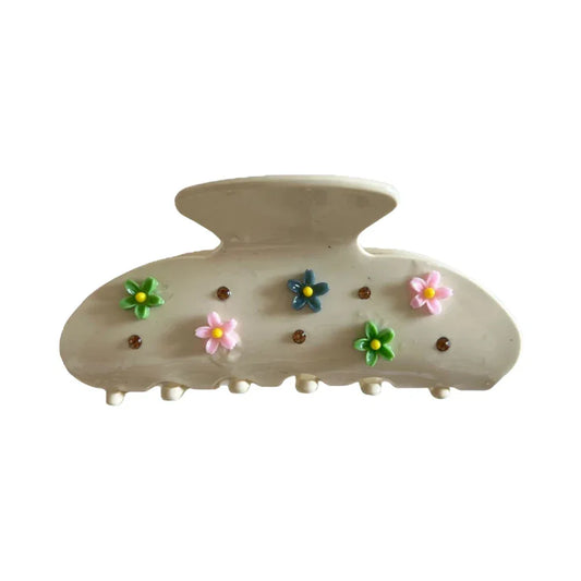 A single cream-colored claw clip adorned with small pastel flowers and brown gemstones.