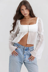 Front view of a woman in a white blouse with a square neckline, plated bodice, and flowing bell sleeves