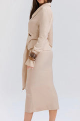 Back view of a woman wearing a beige linen blend long-sleeved top and midi skirt.