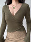 Woman wearing a green ribbed wrap top with a butterfly necklace and a tan lace skirt