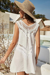 Back view of a woman wearing a white crochet trim tunic dress and straw hat.